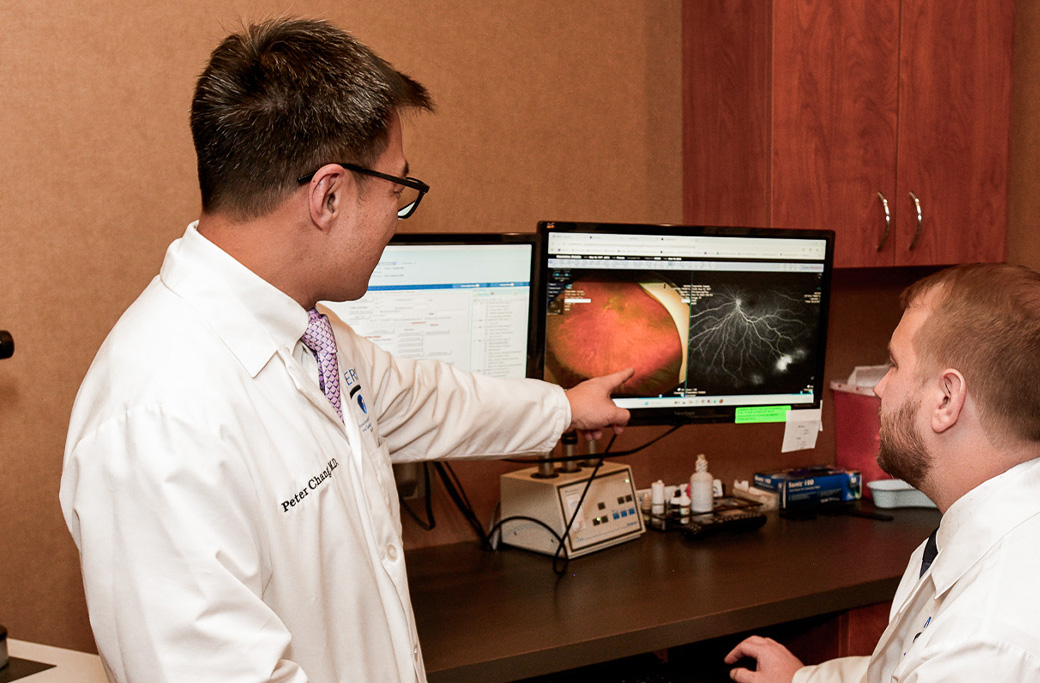 Retina specialist reviewing detailed retinal imaging with a patient at an eye-care appointment.